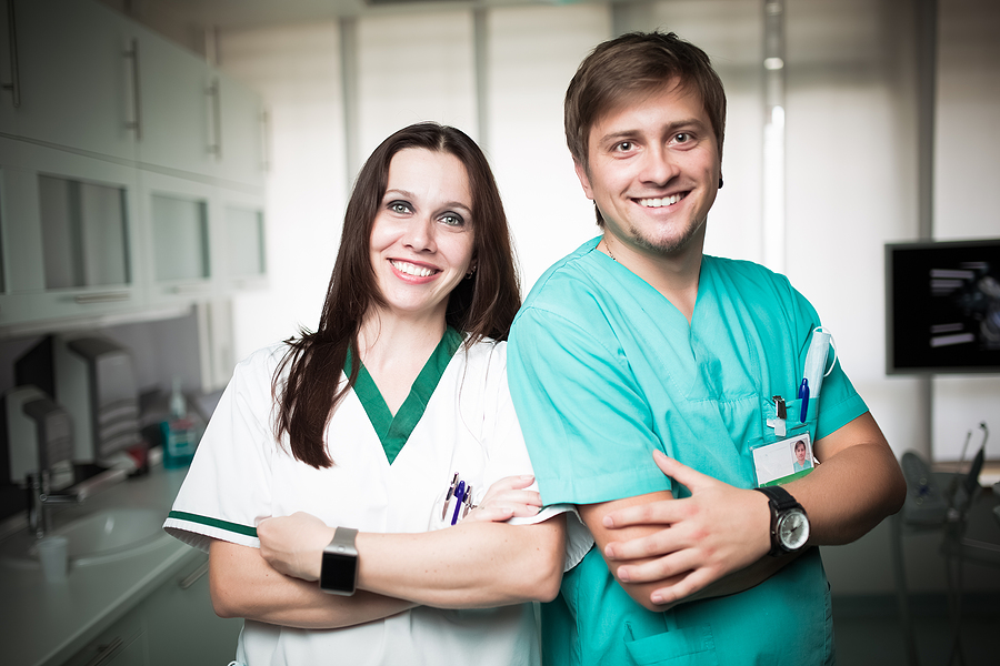 Female and male medical assistants posing together in a medical office